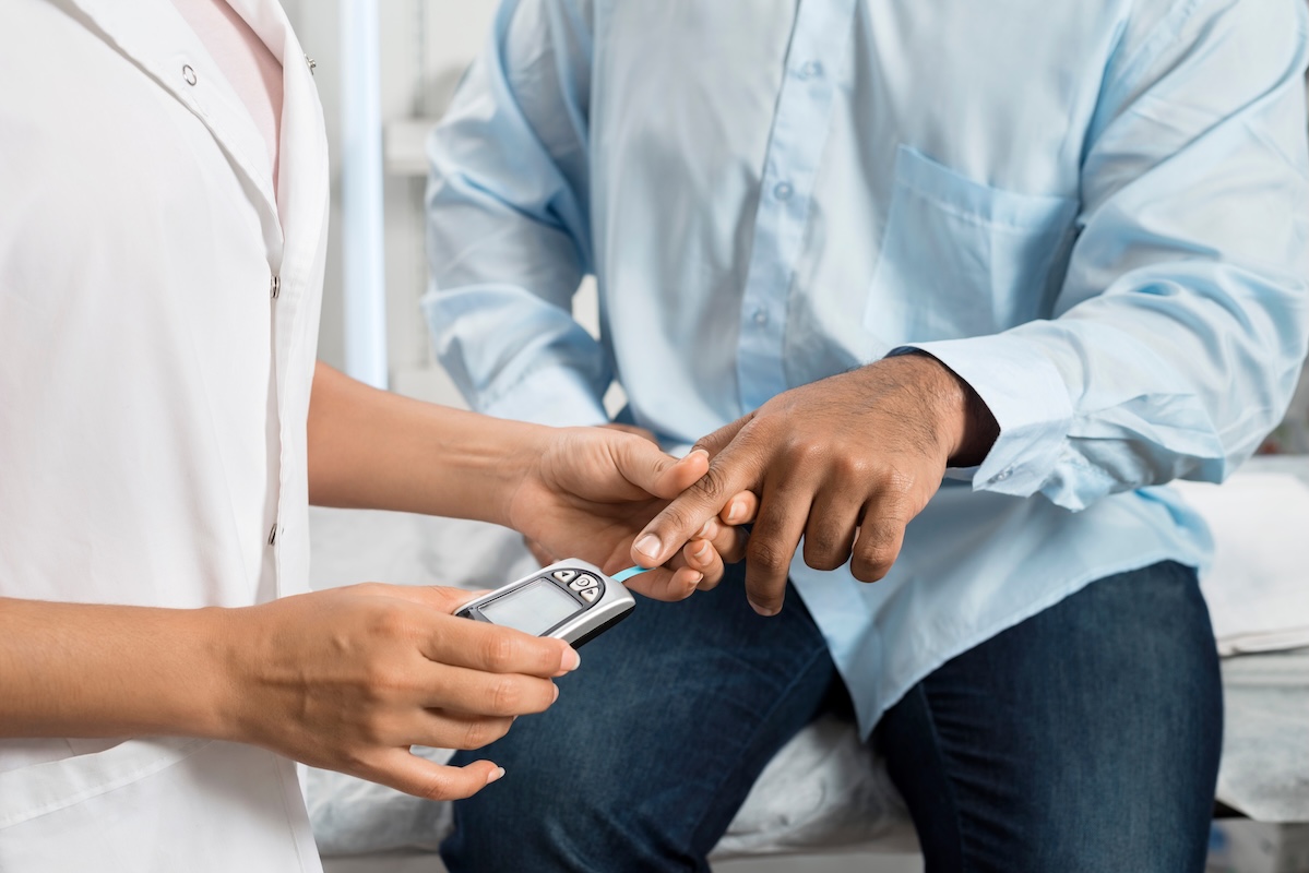 doctor examining sugar level of young patient with glucometer in pharmacy