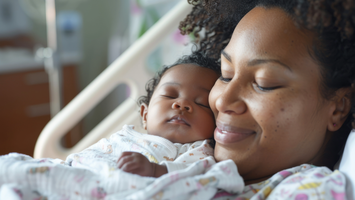 Mom smiling while holding her newborn baby in hospital bed